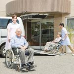 施設の玄関前で車いすを利用する入居者と職員の様子